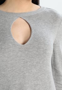 Grauer Strickpullover mit Rundhalsausschnitt und zentralem Ausschnitt. Weiche Textur und nahtloses Design. Keine zusätzlichen Muster oder Verzierungen.