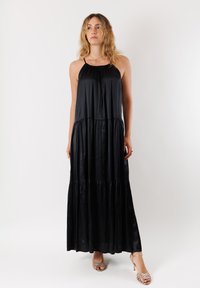 Abito maxi nero realizzato in tessuto morbido con un design a strati e livelli. Presenta spalline sottili e una vestibilità comoda. Messo in risalto da una silhouette fluida.