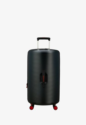 Valise rigide noire avec texture à nervures horizontales, poignée en aluminium extensible et accents rouges sur les roues et le logo de la marque.