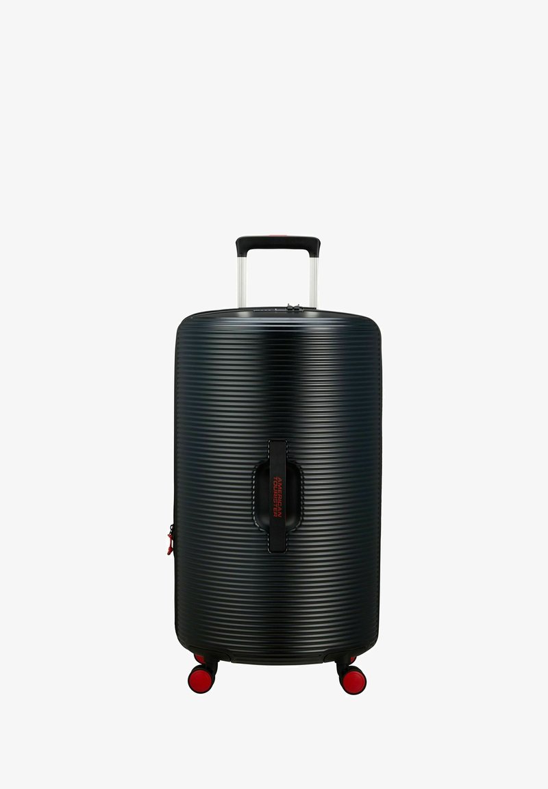 Valise rigide noire avec texture à nervures horizontales, poignée en aluminium extensible et accents rouges sur les roues et le logo de la marque.