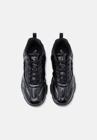 Fekete sportcipők fényes felülettel. Fűzős kialakítás, texturált panelek és húzópántok a saroknál. Lélegző hálós bélés.