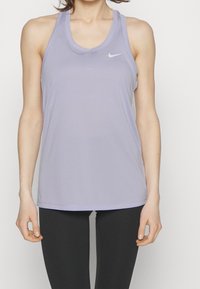 Jasnolawendowy top bez rękawów wykonany z miękkiego, odprowadzającego wilgoć materiału. Posiada okrągły dekolt i subtelne białe logo Nike na klatce piersiowej.