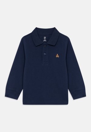 Polo de manga larga azul marino con cuello acanalado, dos botones y un pequeño logo dorado en el pecho. Material de algodón con un acabado texturizado.