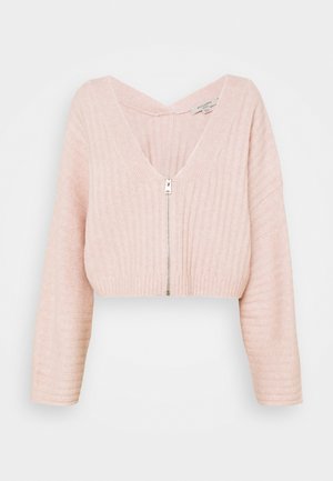 Weiche, rosa gerippte, kurze Strickjacke mit langen Ärmeln und einem zentralen silbernen Reißverschluss, ausgestattet mit einem V-Ausschnitt und lockerem Sitz.