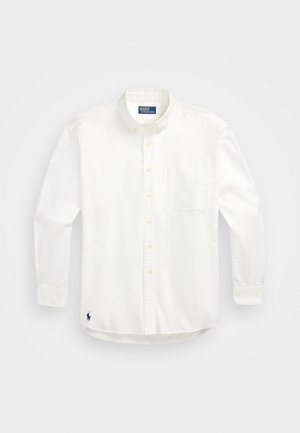Wit overhemd met lange mouwen, knopen, borstzak en een klein geborduurd marineblauw logo vlak bij de onderkant.