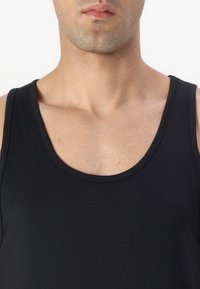 Top negro sin mangas con escote redondo y amplias sisas, fabricado en suave algodón y con un diseño ajustado.