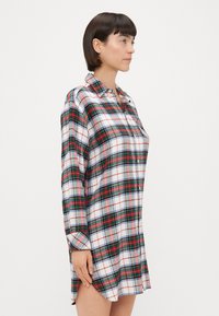 Abito a camicia in cotone a quadri, con motivi a controllo verdi, rossi e blu. Maniche lunghe, colletto e chiusura frontale con bottoni.