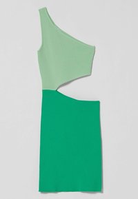 Robe asymétrique avec une texture côtelée, présentant un haut vert clair et un bas vert uni. Un détail découpé met en valeur le design.