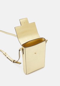 Piccola borsa a tracolla rettangolare in pelle dorata, con patta aperta e tracolla regolabile, appoggiata su una superficie bianca.