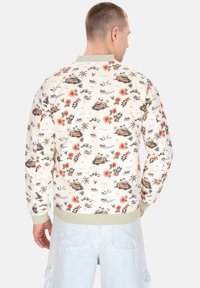 Crème sweatshirt met bloemenpatroon, featuring palmbomen en boten. Geribbelde manchetten en kraag in lichtgroen. Ontwerp met een relaxte pasvorm.