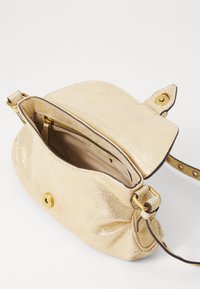 Goldfarbene metallische Lederhandtasche mit runder Form, einer Vorderklappe, einem Reißverschluss-Innenfach und einem verstellbaren Riemen. Vorderer Snapverschluss.