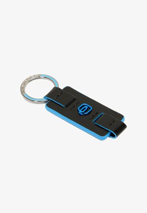 Zwart en blauw sleutelhanger met rechthoekige vorm, voorzien van een glimmende zilveren ring en verhoogde letters in blauw, bevestigd met een zwarte riem.