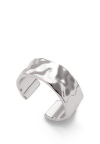 Brazalete de plata con una superficie pulida y ondulada, que presenta un diseño abierto y bordes suaves, reflejando la luz con un acabado brillante.