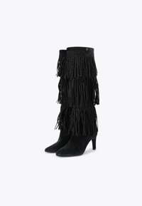 Czarne zamszowe botki za kostkę z warstwowym detalem frędzlów i szpilką. Mają teksturowaną powierzchnię i smukły kształt.