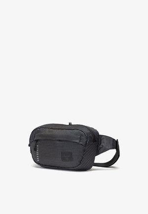 Black fabric waist bag with a grid pattern, zippered compartments, adjustable strap, and a brand label on the front. Textured surface.