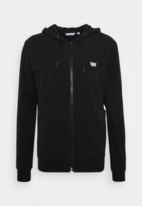 Felpa nera con zip realizzata in morbido misto cotone, con cappuccio piatto, cordino, tasche laterali e un piccolo logo sul petto.