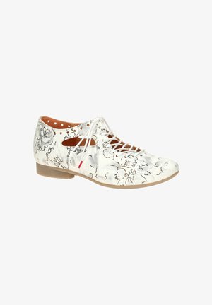 White low-heeled lace-up shoe with black floral patterns and side cutouts, featuring beige sole and tan interior lining.