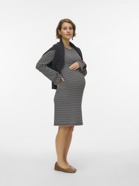 Ριγέ μαύρο και λευκό φόρεμα, εφαρμοστή γραμμή, μήκος μέχρι το γόνατο. Φορεμένο με σκούρο υφασμάτινο τοπ. Καφέ μπαλαρίνες. Απλά σκουλαρίκια. Ανοιχτό φόντο.