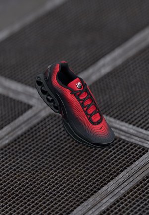 Roter und schwarzer Sportschuh mit einem Obermaterial aus Mesh, einem ausgeprägten Schnürsystem, einer gepolsterten Sohle und einem markanten Luftkammerdesign.