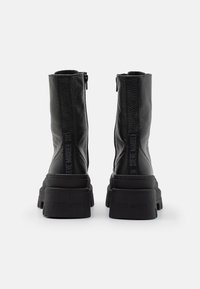 Black ankle boots feature a textured leather upper, a chunky sole, and a side zipper. The brand name is embossed on the heel.
