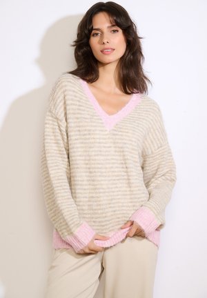 Prevelik bež in roza pulover z V-izrezom, s prijetno teksturo ter kontrastnimi roza manšetami in vratnim trakom.
