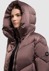 Gewatteerde pufferjas in mauve met een grote, gestructureerde capuchon. Voorzien van een rits aan de voorkant, drukknoopsluitingen en een zwart logo op de mouw.