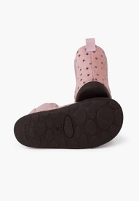 Różowe buty z wzorem gwiazdek na cholewce, z teksturowaną czarną gumową podeszwą i z pętelką z tyłu do łatwego zakładania.