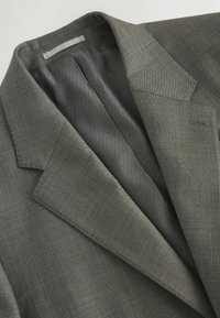 Grauer Blazer aus strukturiertem Stoff, mit Reverskragen und glattem Innenfutter, das ein dezentes Diamantmuster aufweist.