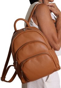 Zaino in pelle marrone con finitura texture, numerose tasche con zip, manico superiore arrotondato e spallacci regolabili.