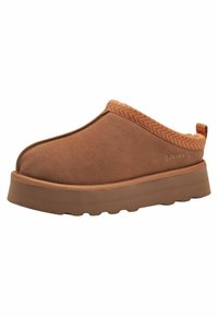 Brun slip-on sko med en ruskindsoverflade, gummisål og zigzag-mønstret tekstiltrim på bagsiden. Har branding på siden.