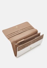 Beige- och vit läderplånbok med flera kortfack, en zip-försedd fack och en guldfärgad tryckknapp. Texturerad yta på den vita delen.