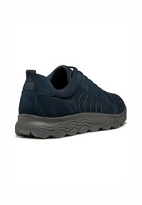 Sneaker in suede blu scuro con una tomaia testurizzata, punta arrotondata e una robusta suola in gomma grigia ondulata. Presenta un anello posteriore per facilitare l'indossamento.
