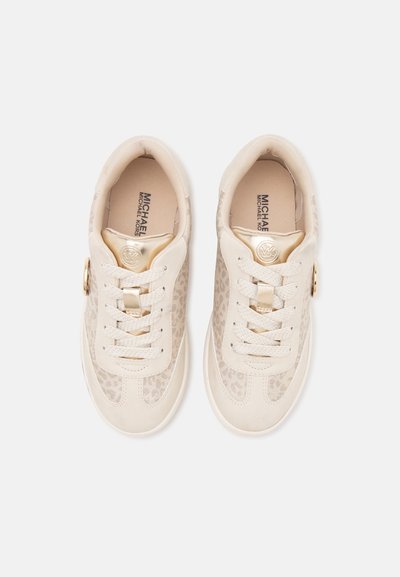 Ζευγάρι μπεζ και ανοιχτόχρυσων sneakers Michael Kors με κορδόνια μπροστά και διακριτική λεπτομέρεια λεοπάρ.