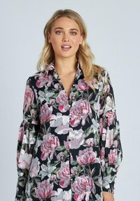 Blusa floreale con grande motivo di peonie rosa su sfondo nero, con colletto e maniche lunghe a sbuffo con dettagli di bottoni.