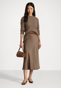 Brun strikket genser med rund hals, beige sateng midi-nederdel, brun belte, liten brun håndveske og brune hæler.
