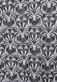 Czarna i biała tkanina z powtarzającym się wzorem stylizowanych twarzy z maseczkami, wirami i kanciastymi akcentami, tworzącym graficzny design.