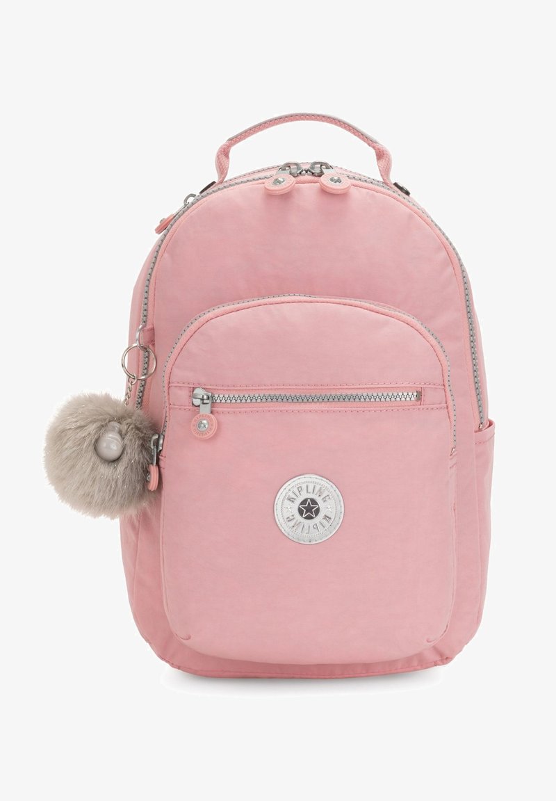 Mochila de nailon rosa con forma redondeada, que cuenta con un bolsillo frontal, herrajes plateados, un accesorio de pom-pom de piel sintética y una insignia de logo circular.