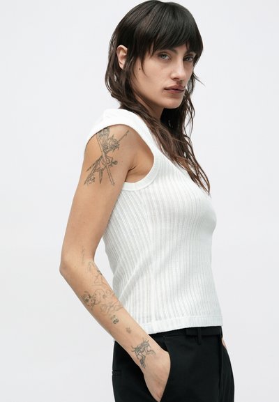 Εφαρμοστό λευκό ριμπ τοπ με φαρδιές τιράντες, διακοσμημένο με υφή και στρογγυλό ντεκολτέ, συνδυασμένο με μαύρο παντελόνι.