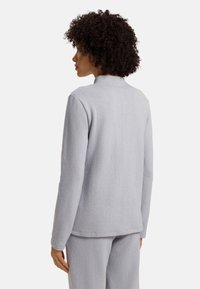 Jasnoszary polarowy sweter z wysokim kołnierzem, długimi rękawami i luźnym krojem. Miękka tekstura z gładkim wykończeniem, minimalistyczny design.