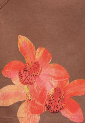 Motif de fleurs d'orchidée orange vif et rose imprimé sur un fond de tissu marron avec des coutures visibles près du bord inférieur.