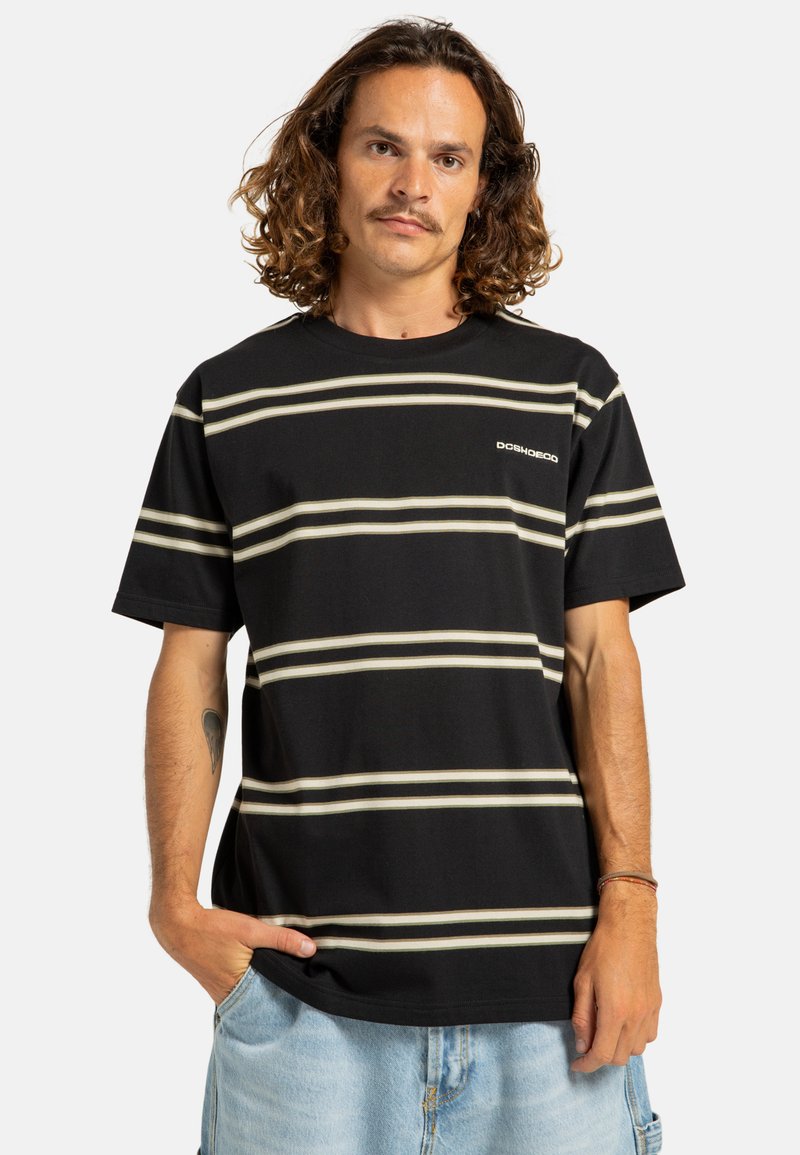 Camiseta negra a rayas con rayas horizontales color crema. Material de algodón, diseño de cuello redondo, mangas cortas y un pequeño logo en el pecho.