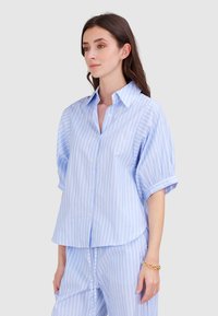 Helleblaue, kurzärmlige Button-up-Bluse mit weißen vertikalen Streifen, klassischem Kragen und hochgekrempelten Ärmeln. Glatte Stofftextur.