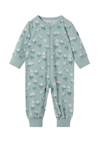 Lys grøn onesie med et blomsterprint af hvide blomster og grønne blade. Lynlås i fuld længde og elastiske manchetter. Blødt stof.