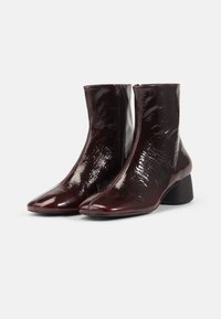 Bordowe botki za kostkę o błyszczącej fakturze, szpiczastej nosie i umiarkowanym obcasie w kształcie bloku; z boku zamek błyskawiczny i smukły design.