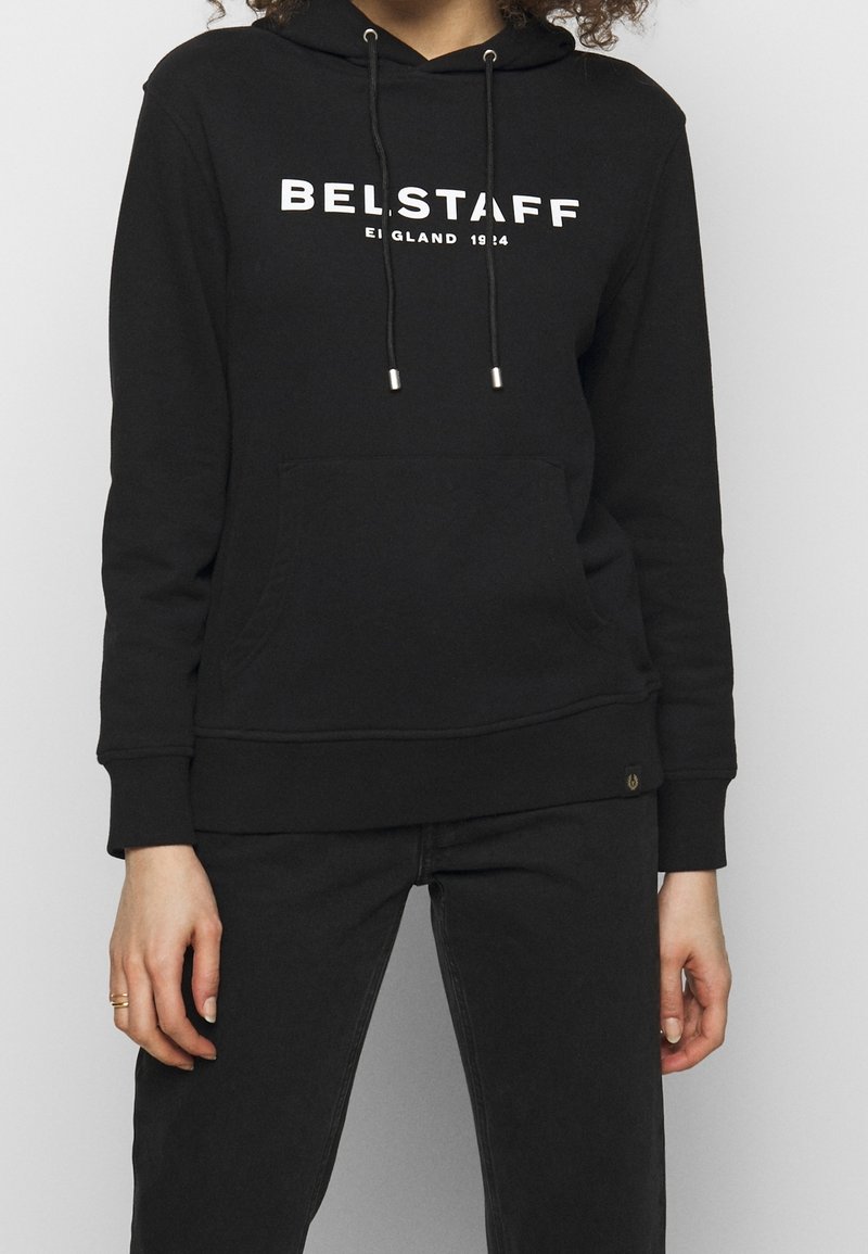 Svart hoodtröja i bomull, med en framlomma, dragskor med metallspetsar och en vit "BELSTAFF"-logotyp tryckt på bröstet.