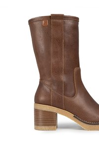Bota de cuero marrón hasta la rodilla con un acabado texturizado, tacón apilado y costuras contrastantes. Panel lateral para un ajuste fácil.