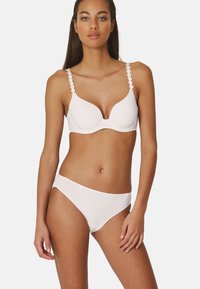 Biały stanik z falbaniastymi ramiączkami i gładkimi, usztywnianymi miseczkami, w zestawie z dopasowanymi, niskimi majtkami bikini z małym detalem w postaci guzika.