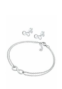 Bracciale infinito in argento e orecchini abbinati. Il bracciale presenta due catene sottili con un simbolo dell'infinito. Gli orecchini hanno un design a perno piccolo.