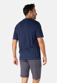 T-shirt en coton bleu marine à manches courtes, associé à un short foncé à motifs géométriques avec une taille élastique.