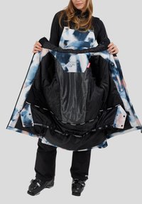 Skijas met een blauw-wit abstract patroon, ritssluiting aan de voorkant en een mesh voering, geopend weergegeven om de binnenkant te tonen.